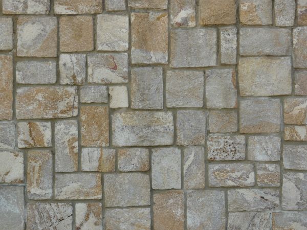 Evenly set multi-colored stone wall in dark grey grout.